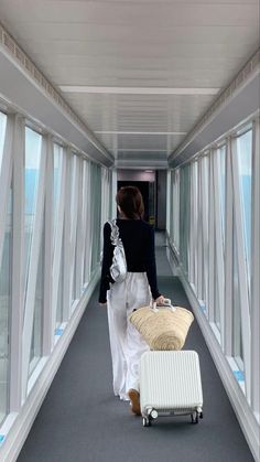 a woman walking down a hallway with a suitcase