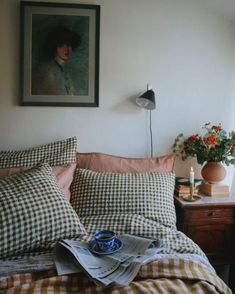 a bed in a room with a painting on the wall above it and a lamp next to it