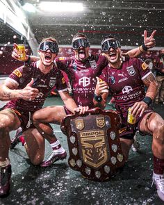 three rugby players pose for a photo with their trophy in front of the camera and confetti falling on them