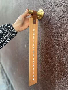 a person's hand holding onto a wooden door handle with the word california written on it