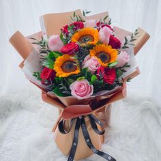 a bouquet of sunflowers and roses wrapped in brown paper with ribbon on white background