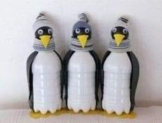 three plastic penguins are standing next to each other with water bottles in their beaks