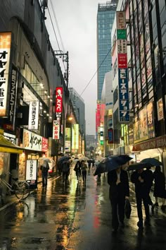 people walking in the rain with umbrellas on a city street near tall buildings at night