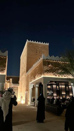 people are standing in front of a building at night