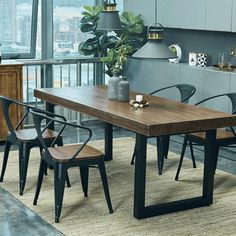 a dining room table with four chairs and a potted plant in the corner next to it