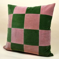 a pink and green checkered pillow on a white background