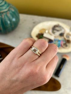 a person's hand with a ring on top of it and other items in the background