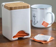 two coffee mugs sitting next to each other on top of a wooden table with orange napkins in front of them