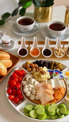 an assortment of food is displayed on a plate with dipping sauces and spoons