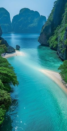 an aerial view of the water and beach in front of some mountains with green trees