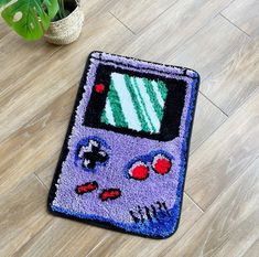 a rug with a gameboy design on the floor next to a potted plant