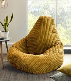 a yellow bean bag chair sitting on top of a wooden floor next to a window