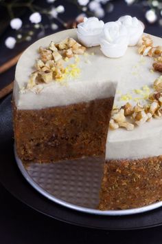 there is a cake with white frosting and nuts on the top, sitting on a plate