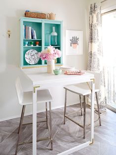 a dining room table with two chairs and a vase filled with flowers