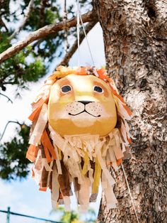 a paper lion head hanging from a tree