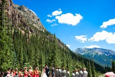 a group of people standing in front of a mountain with trees and mountains behind them