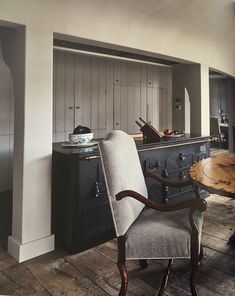 a chair sitting in front of a table with an old trunk on it's back