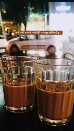 two shot glasses filled with liquid sitting on top of a table next to each other