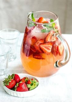 a pitcher of water with strawberries in it