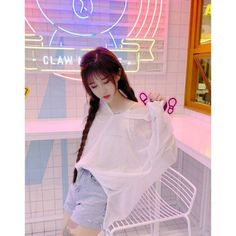 a girl with long hair standing next to a white chair in a room filled with neon signs