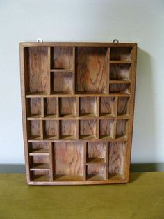 a wooden shelf with compartments on it sitting on top of a table next to a wall