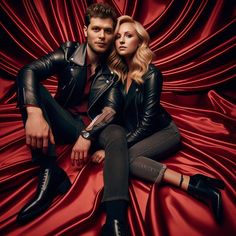 a man and woman sitting next to each other on a red cloth covered floor with black shoes