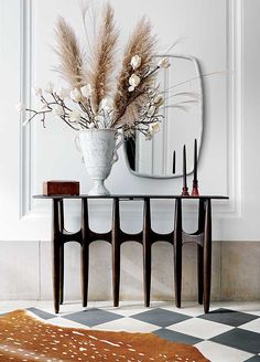 a vase with flowers on a table in front of a mirror and checkered floor