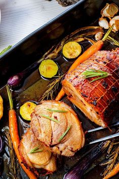 a roasting pan filled with meat, vegetables and carrots on top of a table