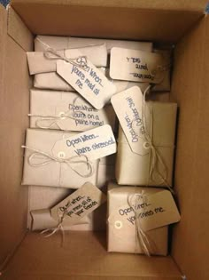 a box filled with lots of white wrapped presents next to some writing on the tags