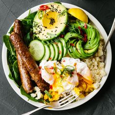 a white plate topped with meat, rice and veggies next to a fork