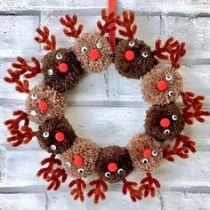 a christmas wreath with reindeer noses hanging on a brick wall