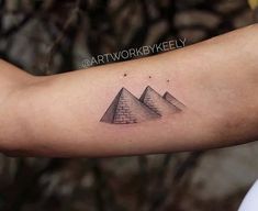 a man's arm with three pyramids tattooed on the upper half of his arm