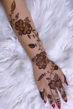 a woman's hand with hennap and flowers painted on it, sitting on top of a fluffy white blanket