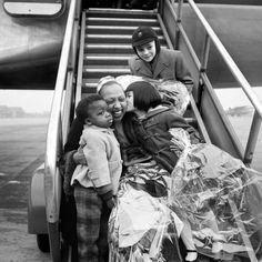 three children are sitting on the steps of an airplane and one is holding another child