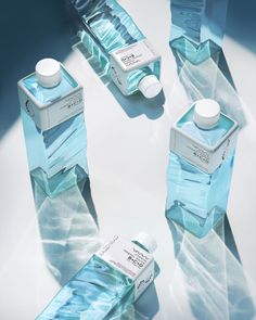 three bottles of blue water sitting on top of a table next to each other with white caps