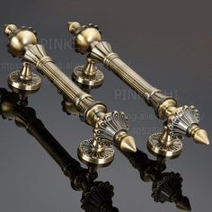 three antique style brass candlesticks with decorative knobs and finials on black background