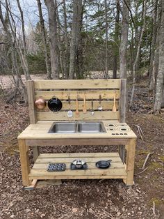 an outdoor sink made out of pallets in the woods with pots and pans on it