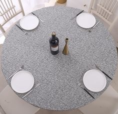 the table is set with white plates and silverware, wine bottle, and two empty glasses