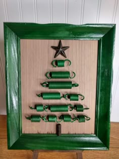 a christmas tree made out of green coils in a frame with a star on top