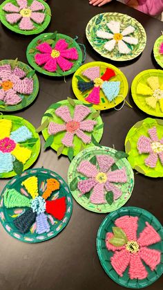 paper plates with crocheted flowers on them sitting on a table next to a child's hand