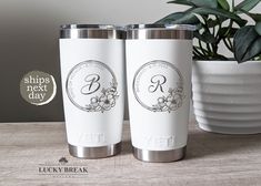 two personalized tumblers sitting on top of a table next to a potted plant