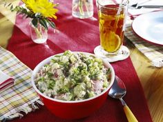 a red bowl filled with food on top of a table next to plates and glasses