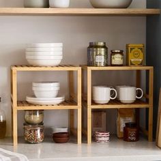 the shelves are filled with bowls, plates and other kitchen ware on wooden shelving