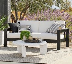 a white couch sitting on top of a wooden table next to a purple flower field