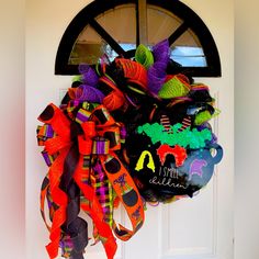 a wreath is hanging on the front door with halloween decorations and ribbons attached to it