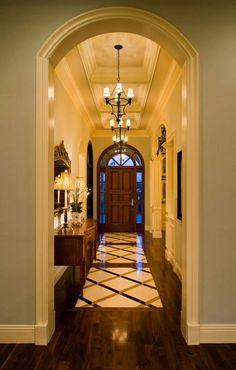 an archway leading into a foyer with wooden floors and chandelier hanging from the ceiling