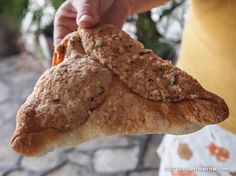 a person holding up a slice of pizza with toppings on it's crust