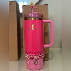 a pink travel mug with an embellished handle