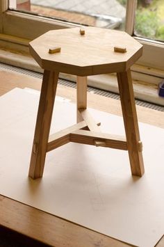 a small wooden table sitting on top of a piece of paper next to a window