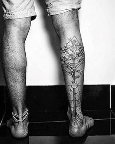 black and white photograph of man with tree tattoo on his lower leg, standing in front of wall